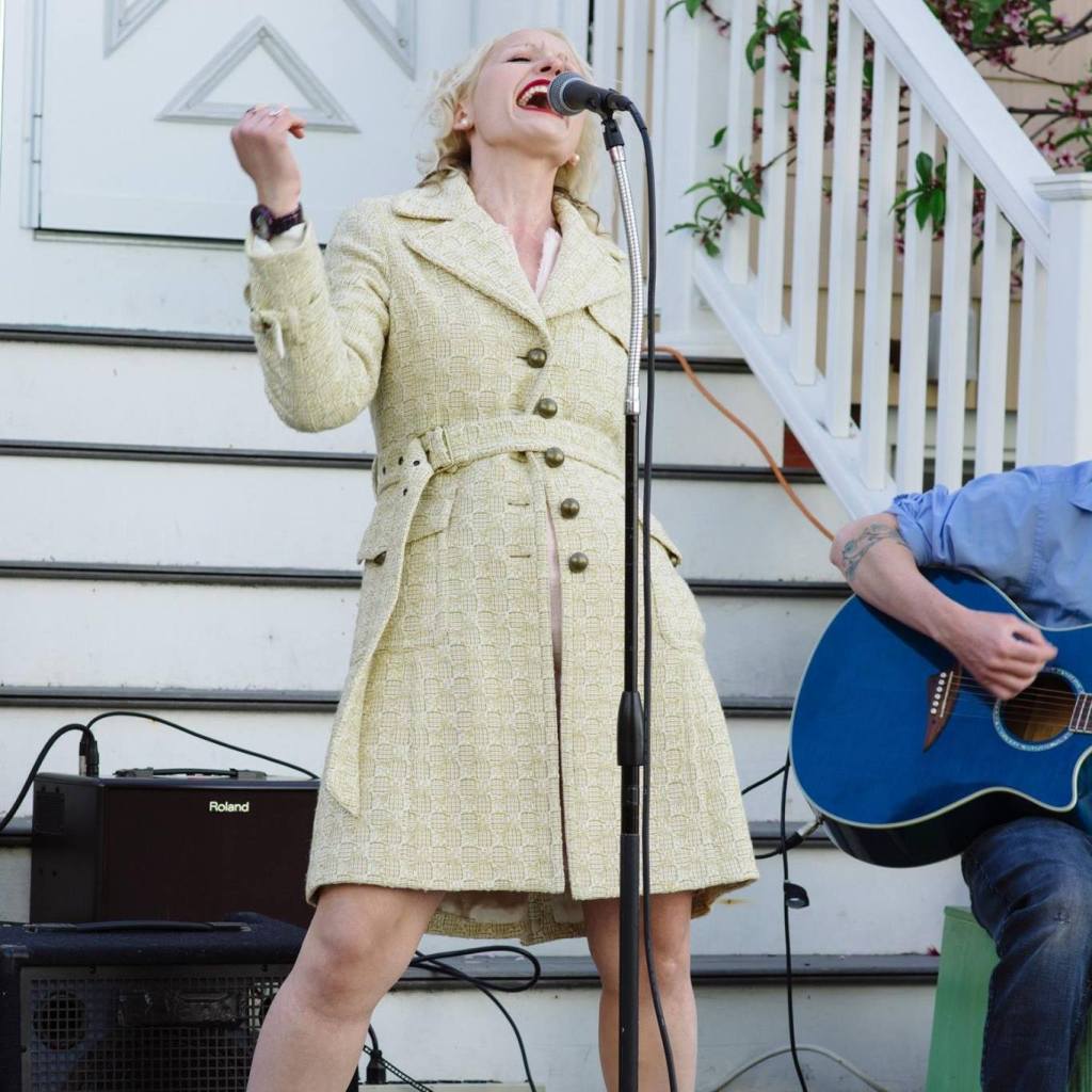 Somerville City Councilor-at-Large Kristen Strezo singing enthusiastically into a microphone at Somerville Porchfest 2018